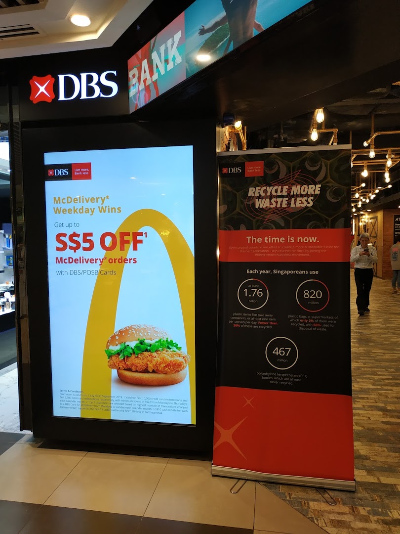 The entrance of DBS Bank at Plaza Singapura, featuring promotional displays for McDelivery and recycling initiatives.