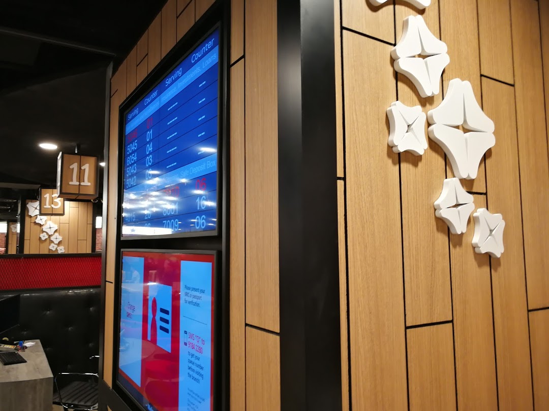 Interior view of a DBS bank branch showing queue screens and a modern waiting area.