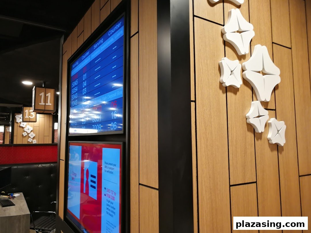 Interior view of a DBS bank branch showing queue screens and a modern waiting area.