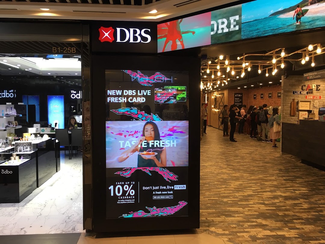The entrance of DBS Plaza Singapura branch featuring a large digital display promoting banking services.