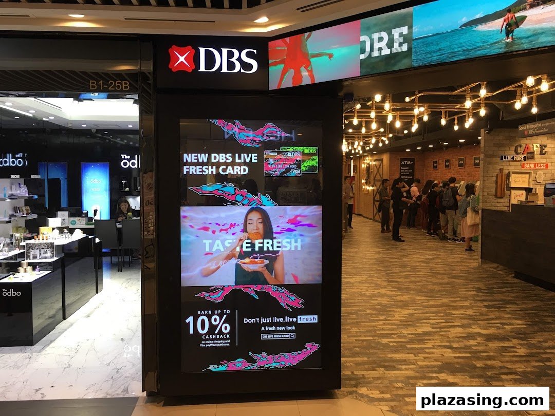 The entrance of DBS Plaza Singapura branch featuring a large digital display promoting banking services.