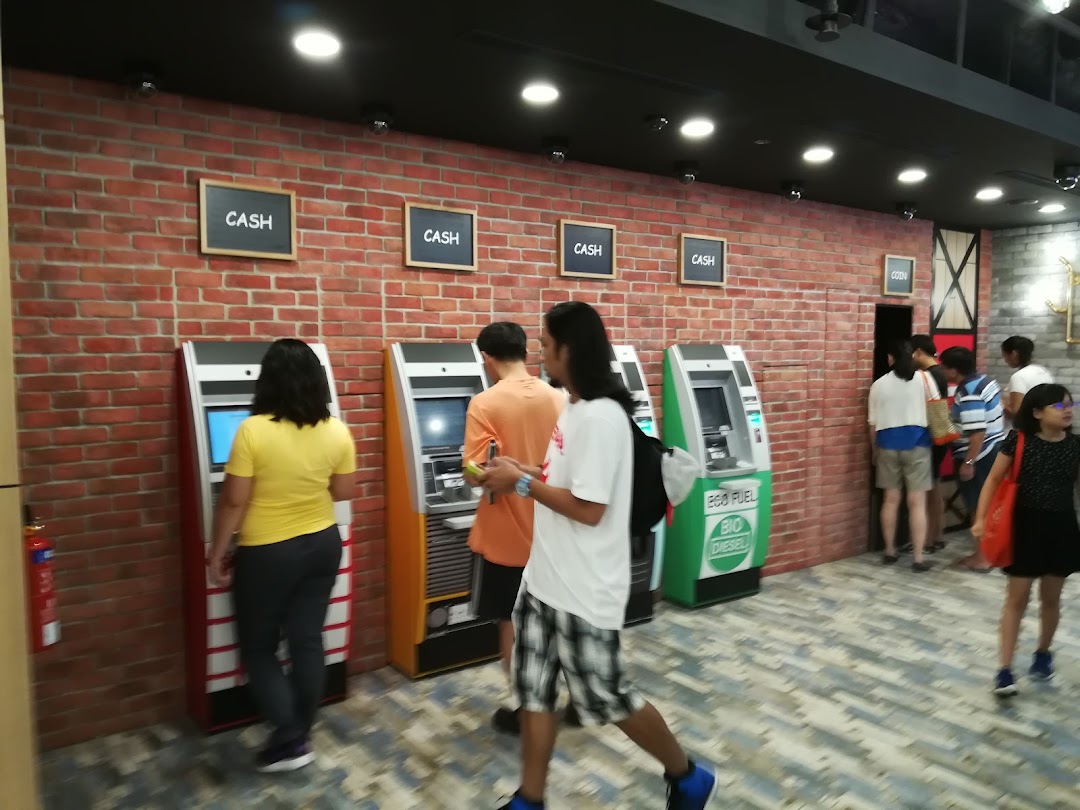 Customers utilize various cash and coin machines within a DBS bank branch, featuring a brick wall aesthetic.