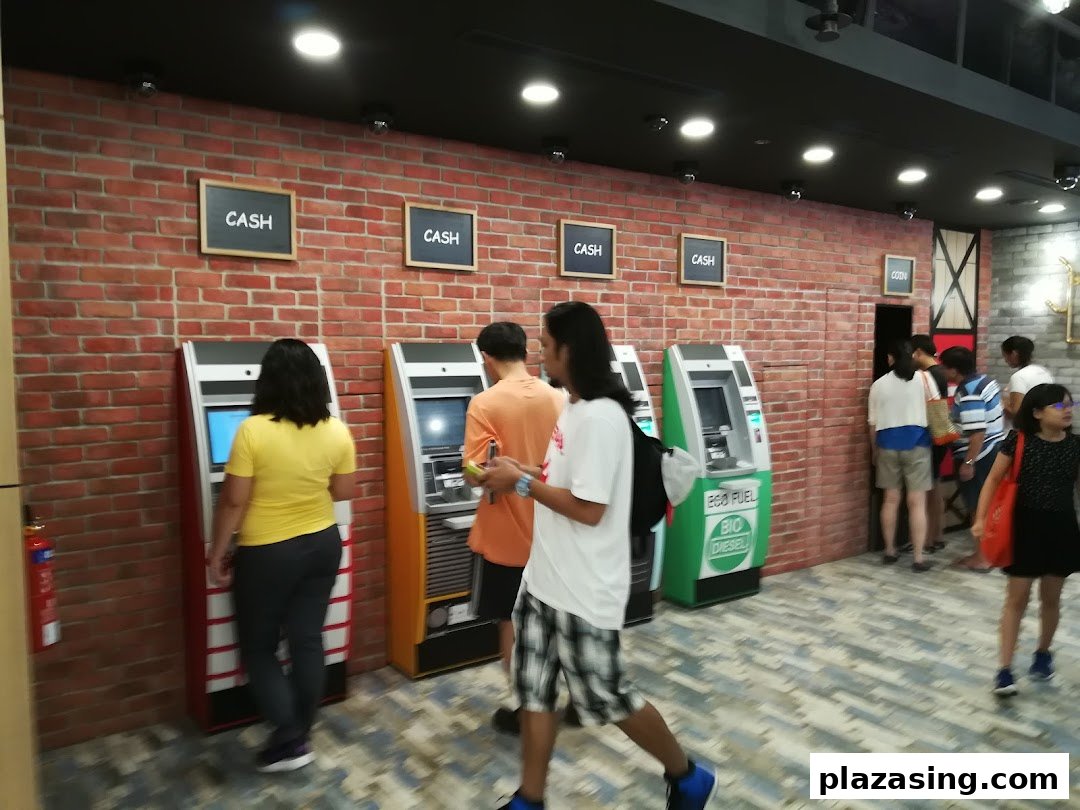Customers utilize various cash and coin machines within a DBS bank branch, featuring a brick wall aesthetic.