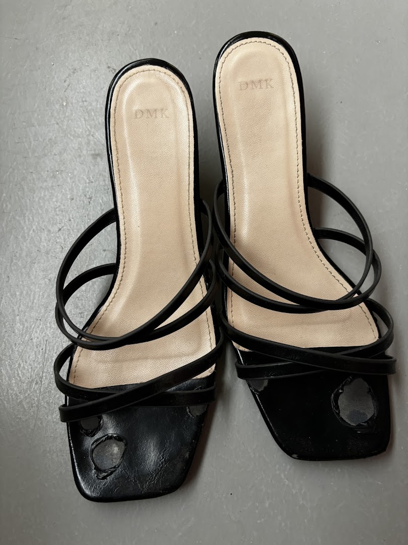 A pair of black strappy sandals with the DMK brand visible on the insoles.