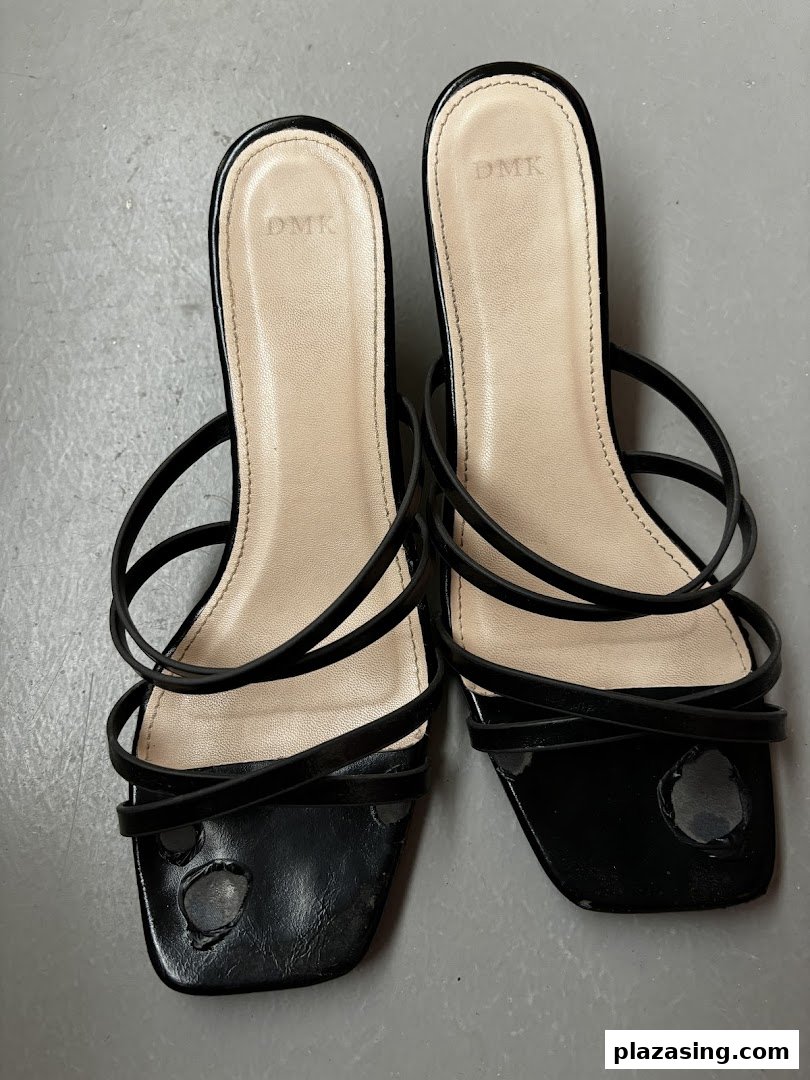 A pair of black strappy sandals with the DMK brand visible on the insoles.