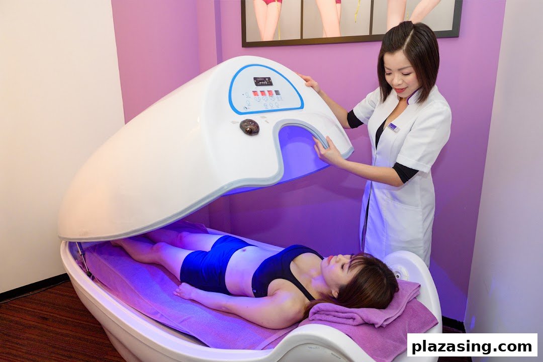 A staff member assists a client undergoing a lower body slimming treatment in a specialized pod.