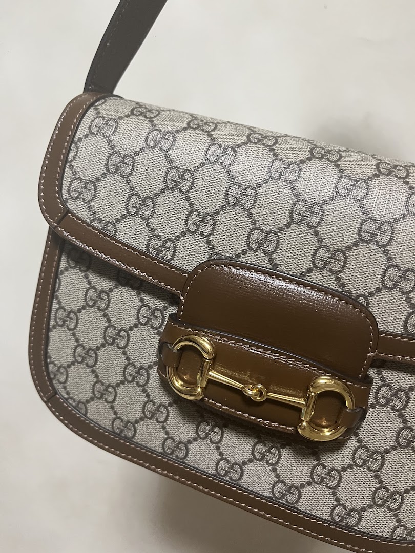 Close-up of a classic monogrammed handbag with a distinctive gold horsebit detail.