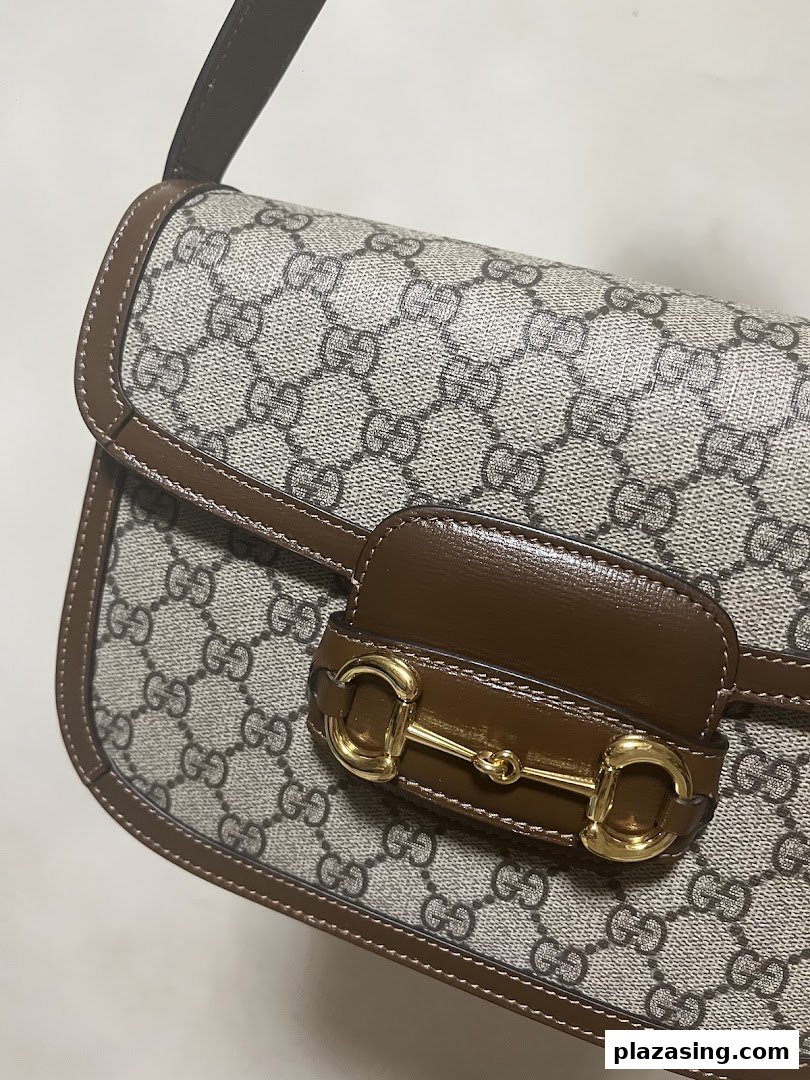 Close-up of a classic monogrammed handbag with a distinctive gold horsebit detail.