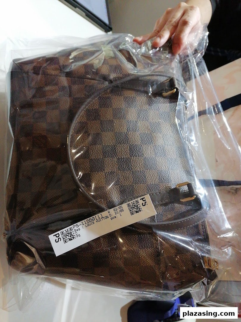 A brown checkered bag, possibly Louis Vuitton, sealed in plastic with a label, being handled.