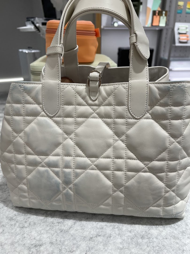 A close-up of a white quilted leather handbag with visible stains, likely awaiting cleaning or restoration.