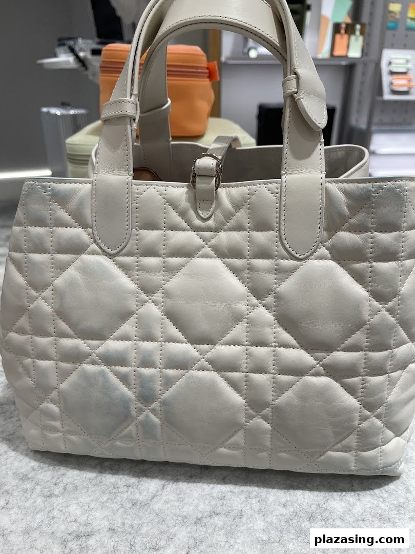 A close-up of a white quilted leather handbag with visible stains, likely awaiting cleaning or restoration.
