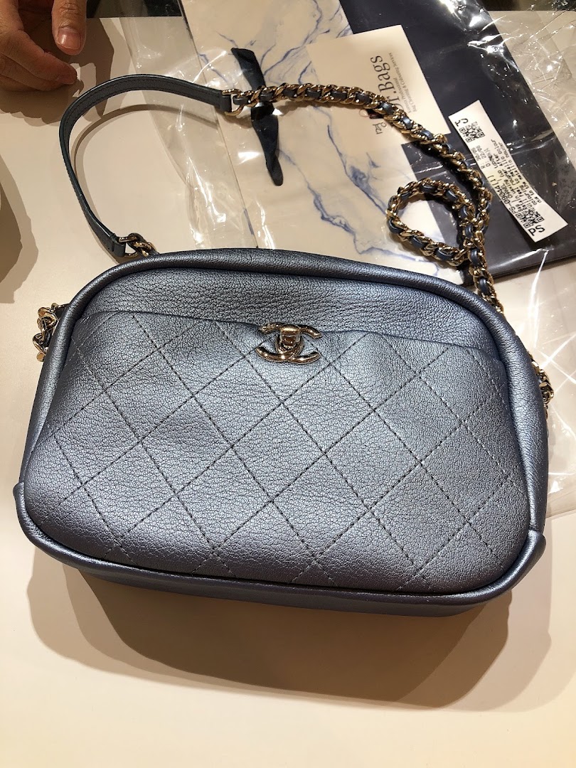 A close-up of a metallic blue quilted handbag with a gold chain strap and CC logo.