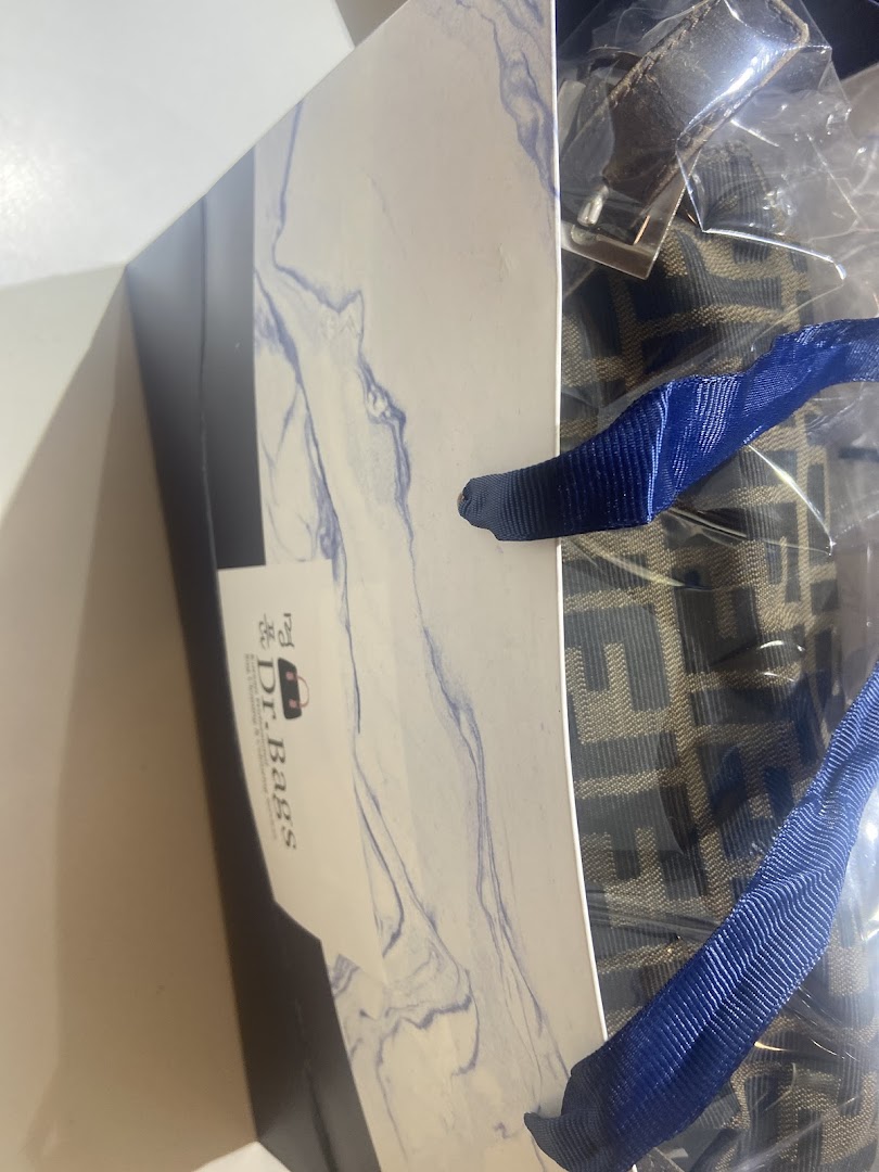 Inside a Dr.Bags shopping bag, revealing a patterned product and blue ribbon handles.