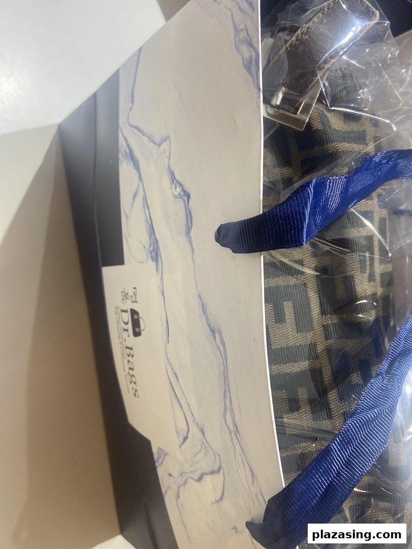 Inside a Dr.Bags shopping bag, revealing a patterned product and blue ribbon handles.