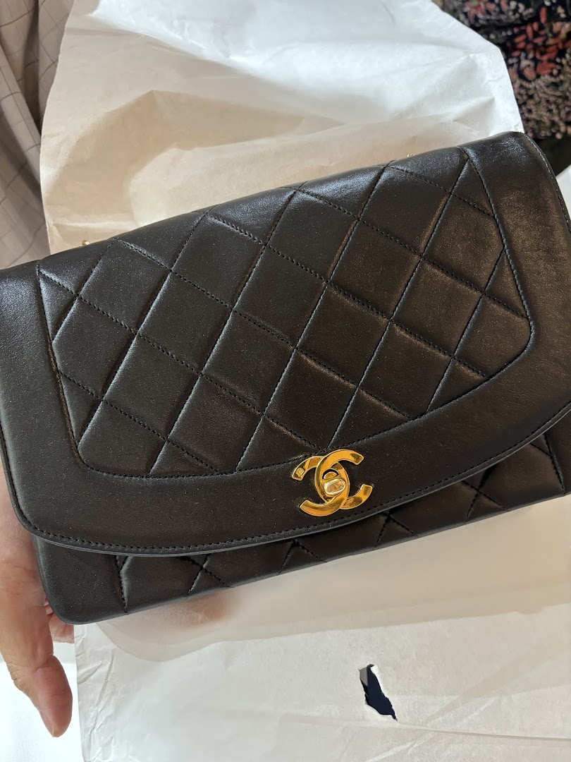 Close-up of a luxurious black quilted handbag with a prominent gold CC logo.