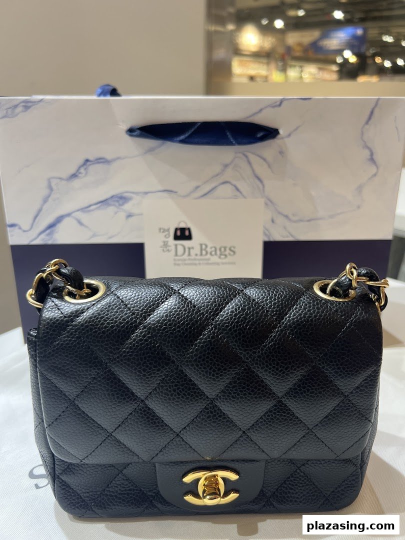 A black quilted handbag with gold hardware in front of a Dr.Bags shopping bag.