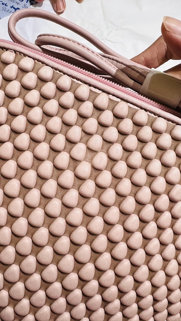 Close-up of a pink textured bag with a unique bubble-like pattern, held by a hand.