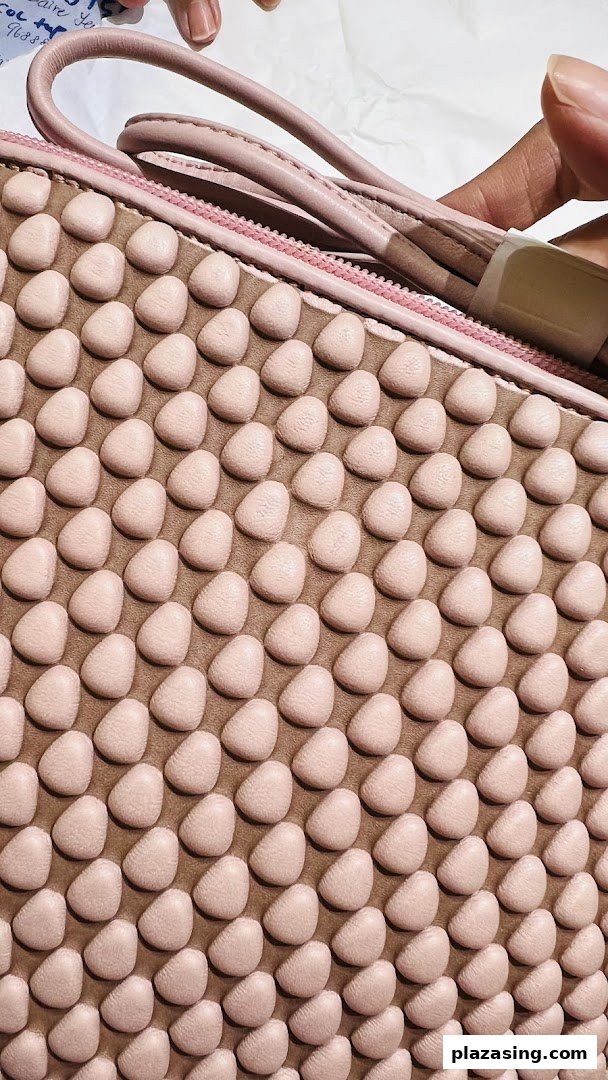 Close-up of a pink textured bag with a unique bubble-like pattern, held by a hand.