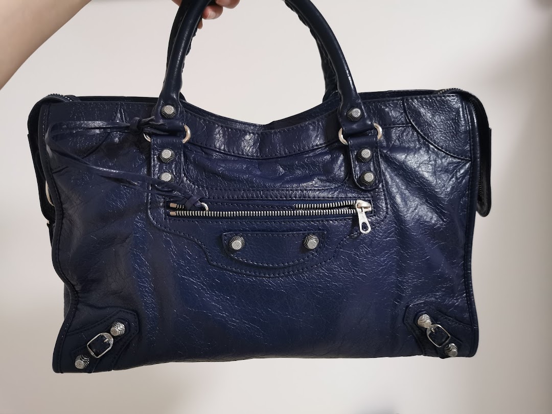 A close-up shot of a stylish dark blue leather handbag with silver hardware.