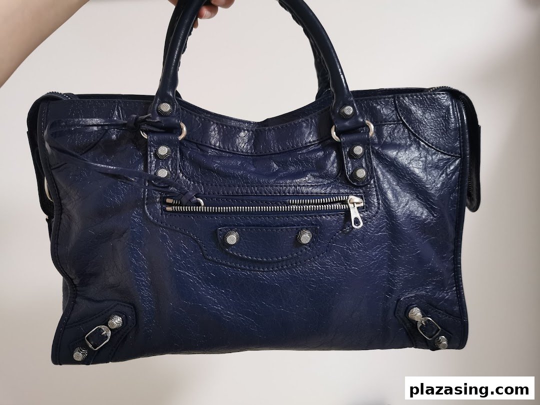 A close-up shot of a stylish dark blue leather handbag with silver hardware.