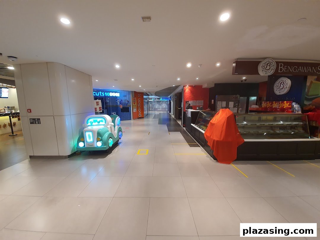 A bright mall corridor featuring shop fronts, a children's ride, and display cases.