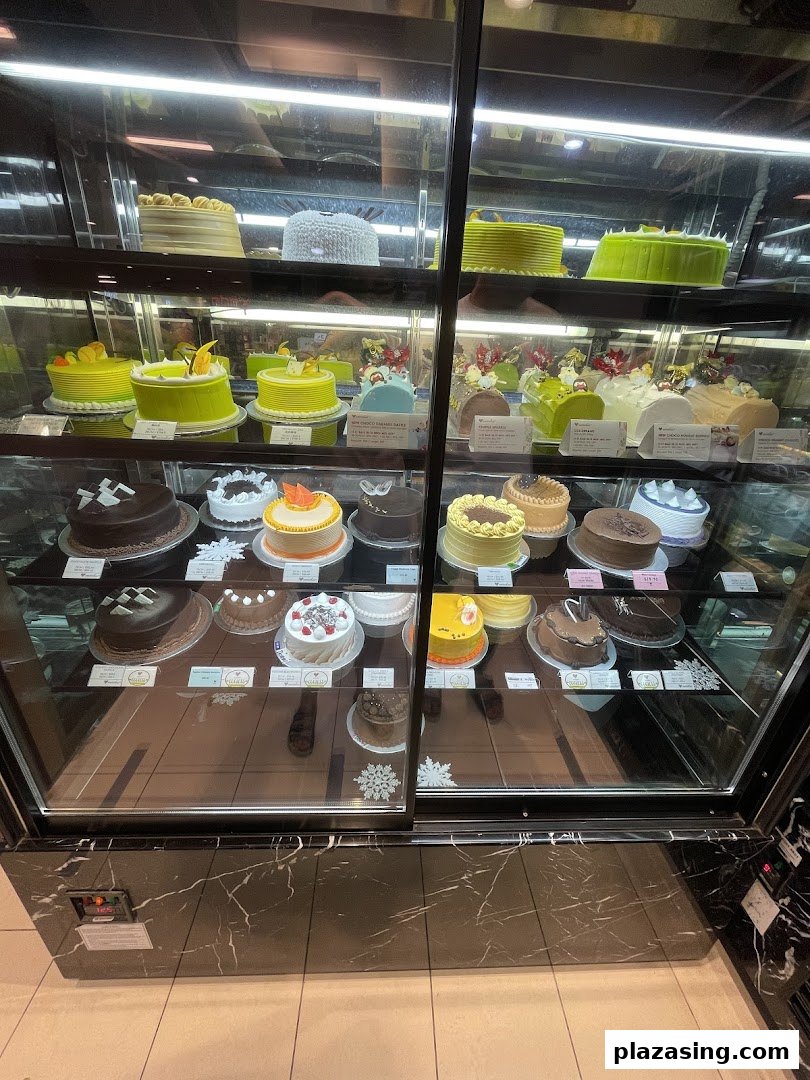 A brightly lit display case showcasing a variety of beautifully decorated cakes and pastries at Emicakes.