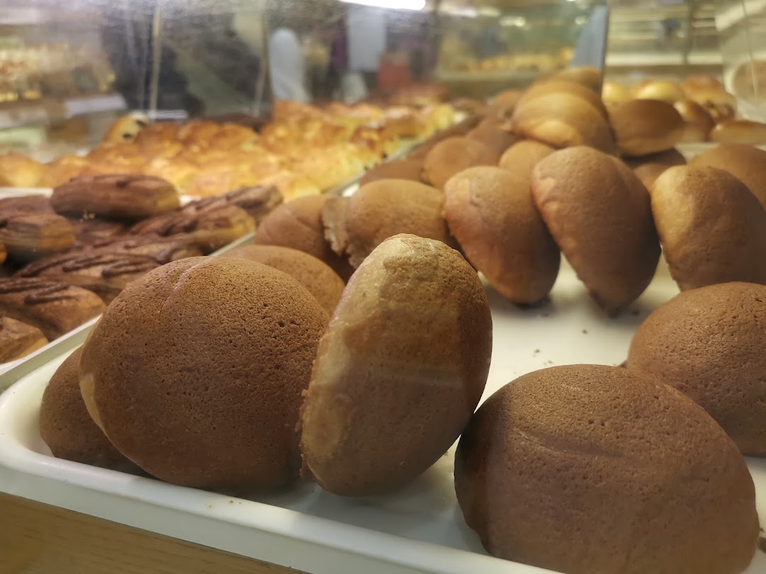 A close-up view of freshly baked coffee buns and other pastries displayed in a bakery case.