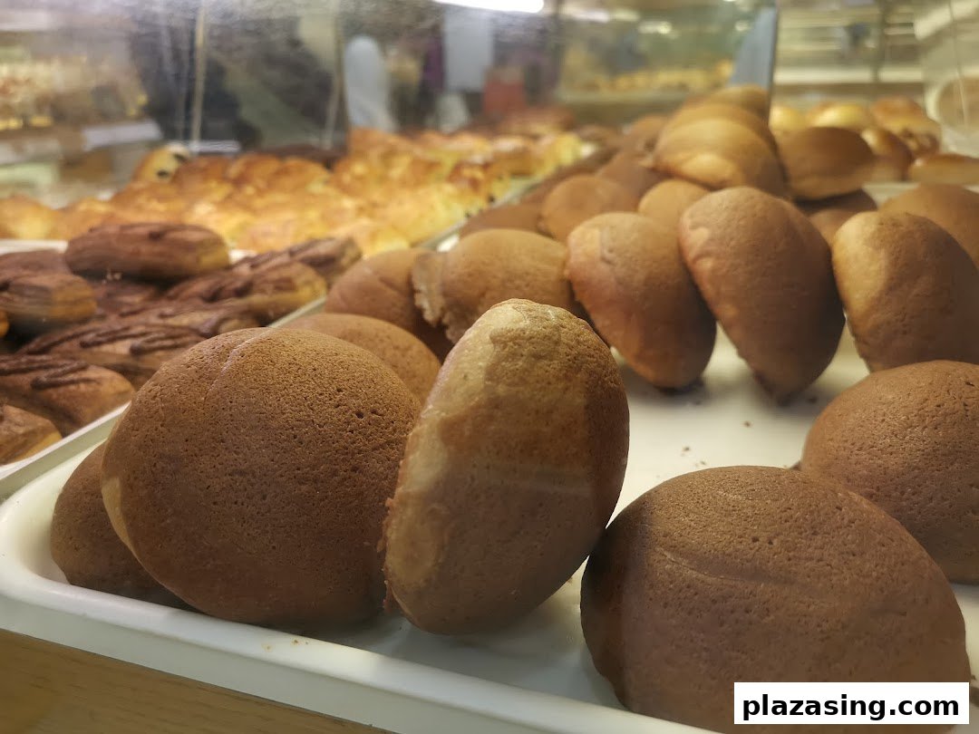 A close-up view of freshly baked coffee buns and other pastries displayed in a bakery case.