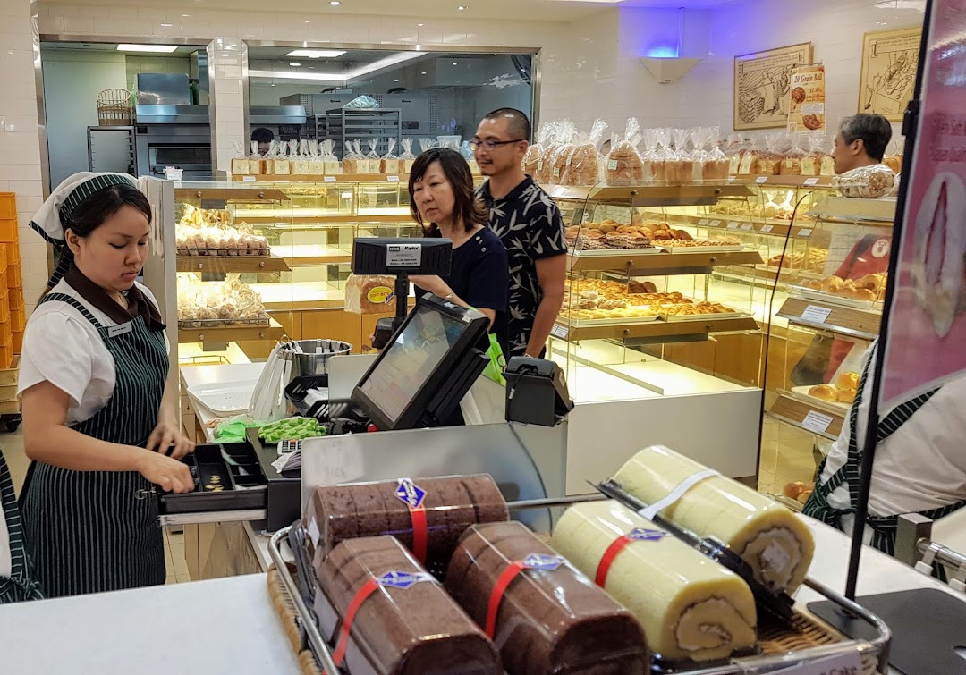 Interior view of Epi Dor bakery with staff, customers, and display cases full of fresh baked goods.