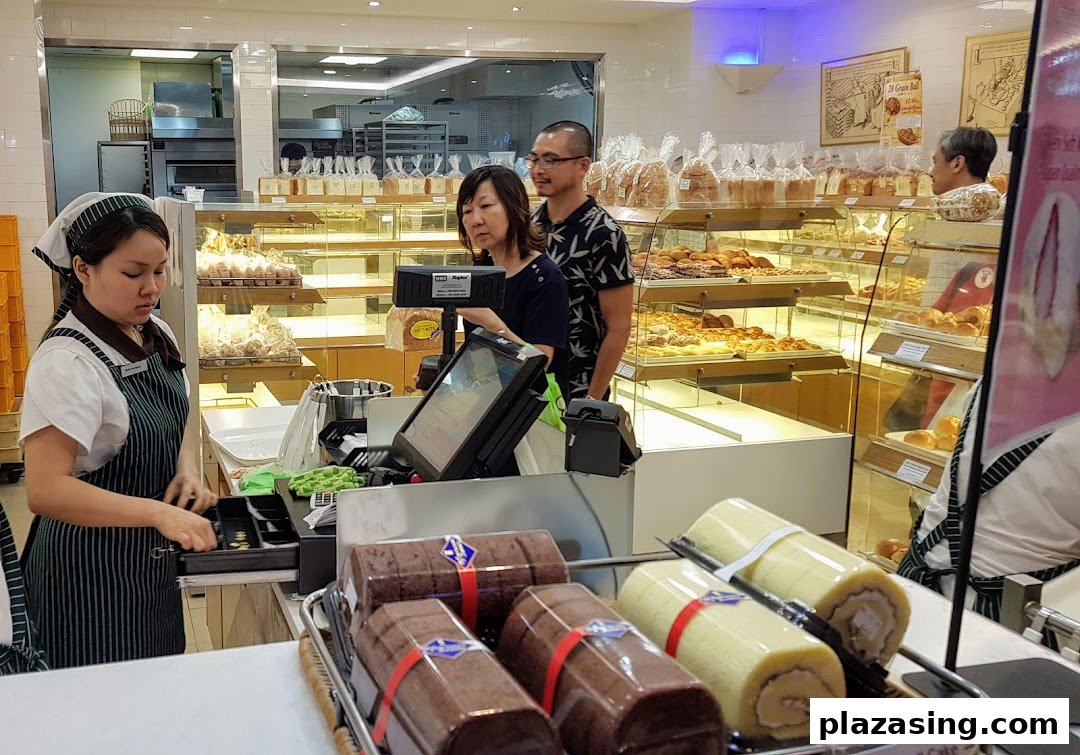 Interior view of Epi Dor bakery with staff, customers, and display cases full of fresh baked goods.