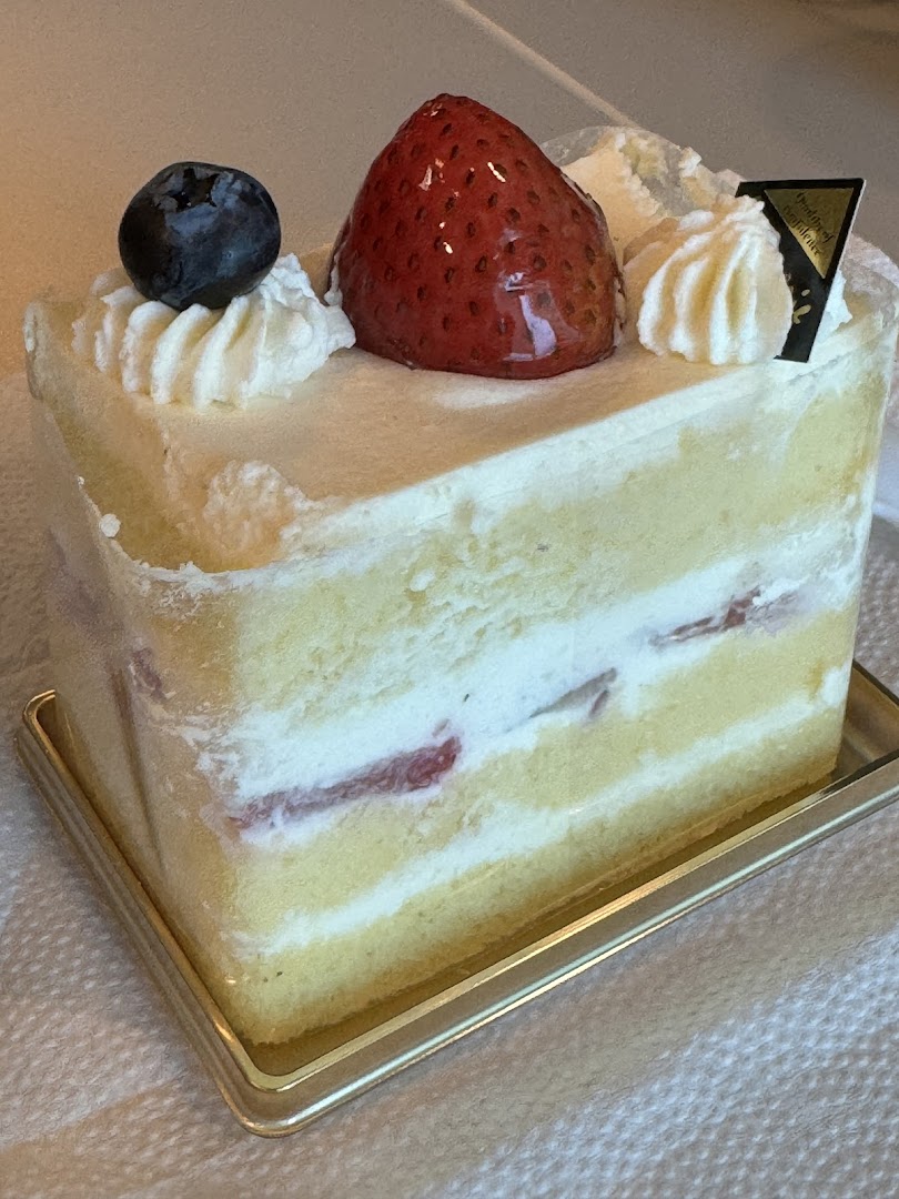 A delicious slice of strawberry shortcake with whipped cream, a strawberry, and a blueberry.