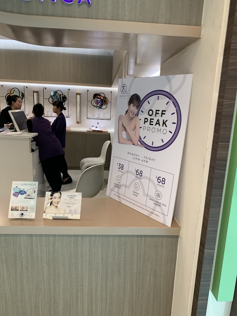 Interior view of Estetica Beauty, showcasing staff at the counter and prominent promotional signs for beauty treatments.