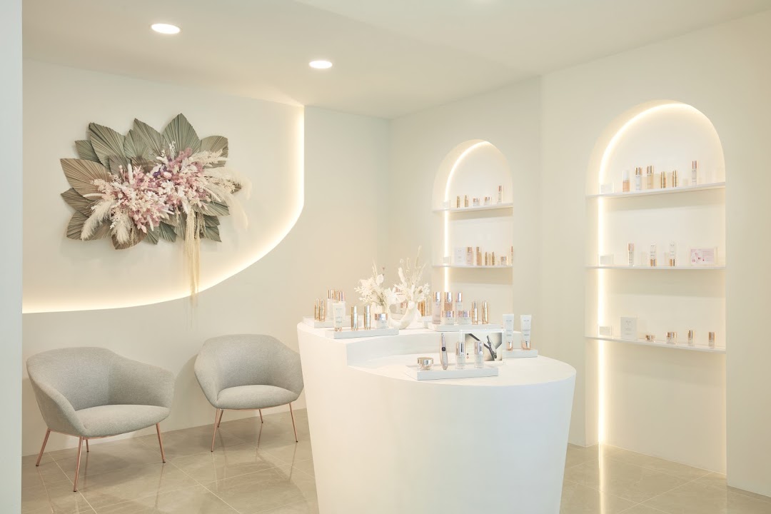 A modern and serene interior of a beauty shop, showcasing skincare products on display and comfortable seating.