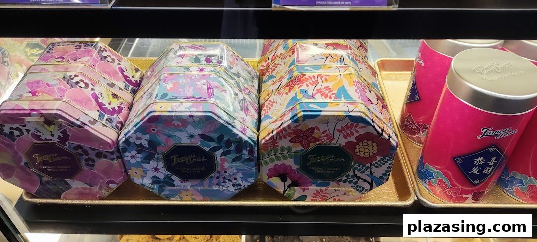 Colorful Famous Amos cookie tins and festive cylindrical containers displayed in a retail case.