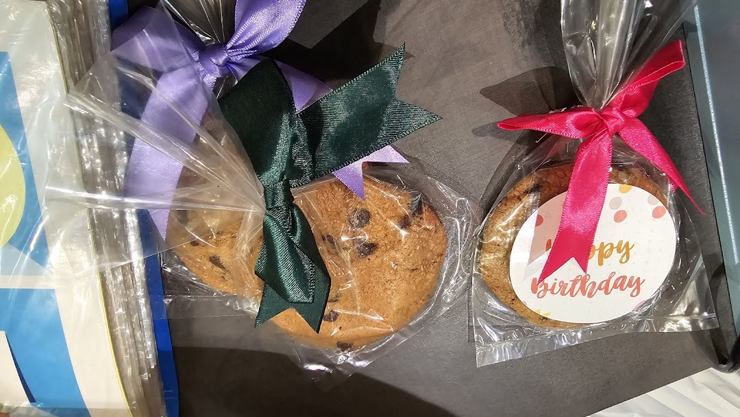 Close-up of individually packaged Famous Amos chocolate chip cookies with decorative ribbons, one with a 'Happy Birthday' tag.