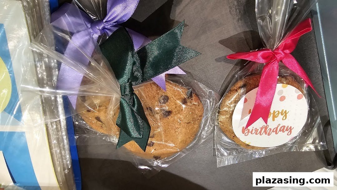 Close-up of individually packaged Famous Amos chocolate chip cookies with decorative ribbons, one with a 'Happy Birthday' tag.