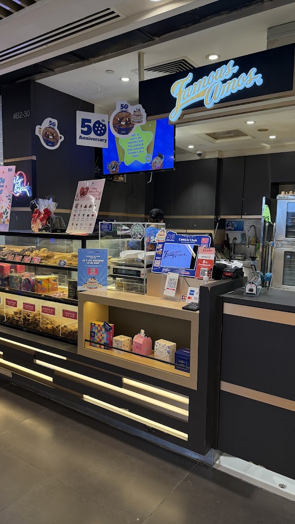 Interior view of Famous Amos cookie shop, showcasing the counter, cookie displays, and branding.