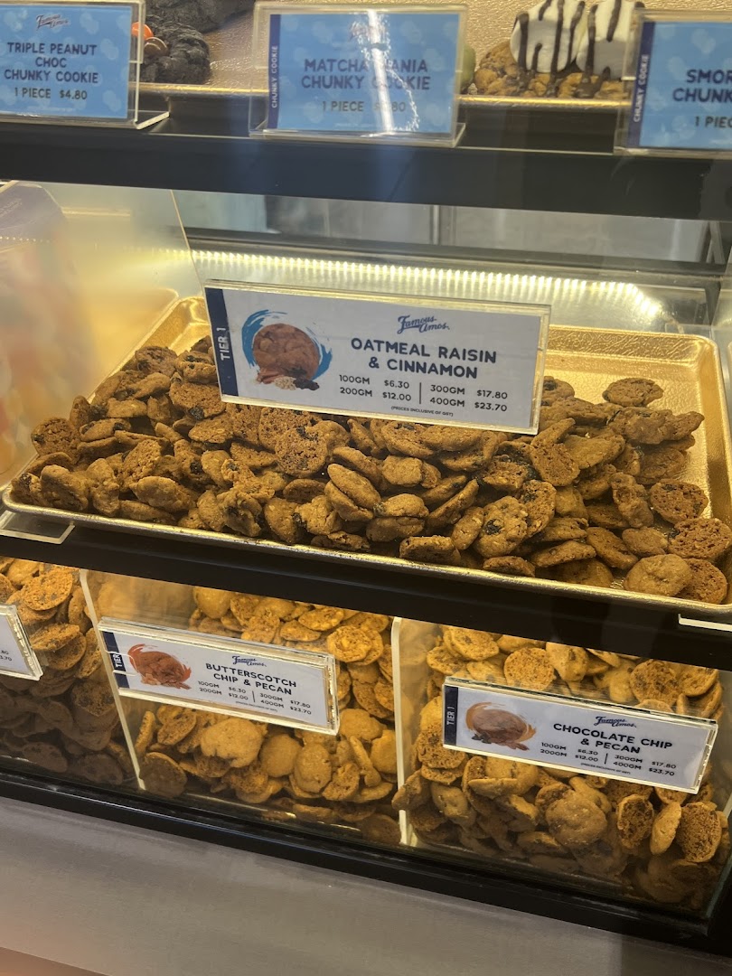 A vibrant display case showcasing various Famous Amos cookies with detailed pricing and product information.