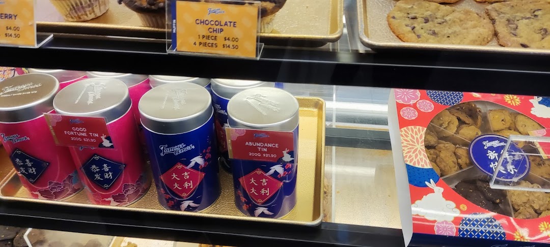A display case at Famous Amos featuring freshly baked cookies, muffins, and festive gift tins.