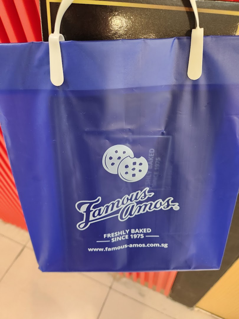 A close-up of a blue Famous Amos shopping bag featuring its logo and cookie graphic.