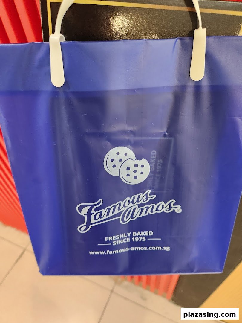 A close-up of a blue Famous Amos shopping bag featuring its logo and cookie graphic.