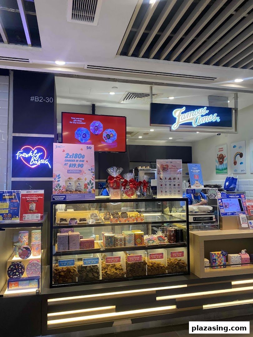 The Famous Amos shop front features cookie display cases, promotional offers, and a 'Freshly Baked' neon sign.