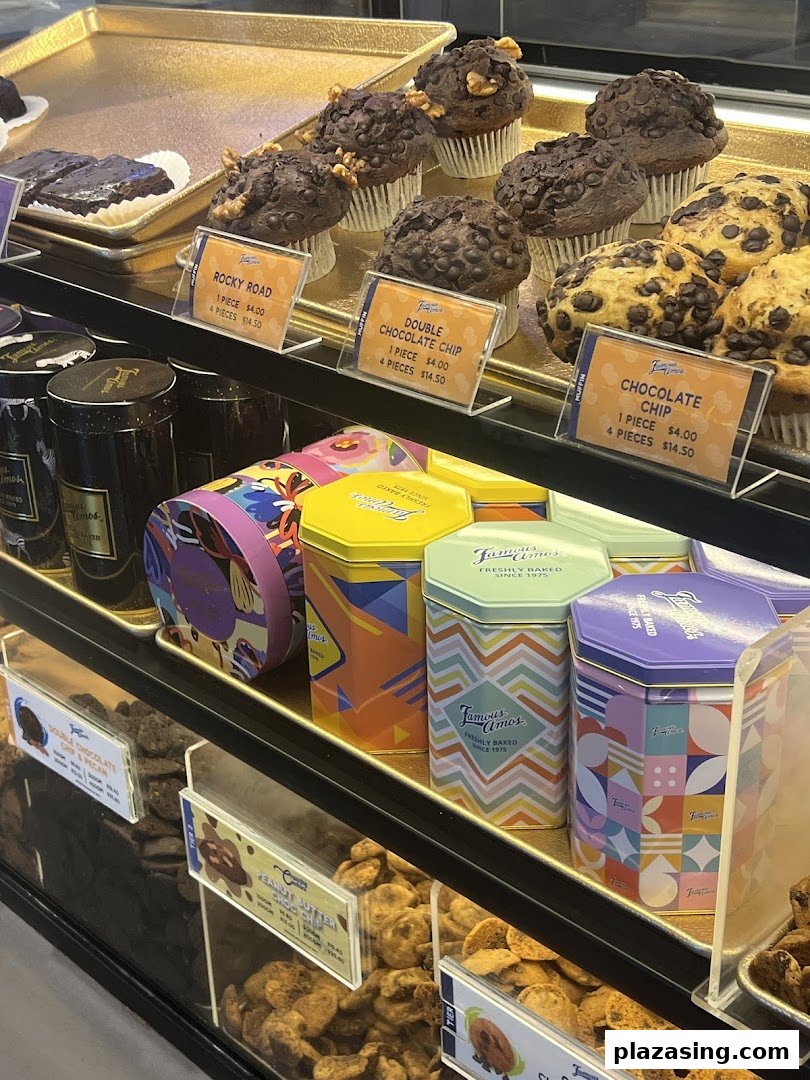 A vibrant display of Famous Amos muffins, cookies, and decorative cookie tins in a retail shop.