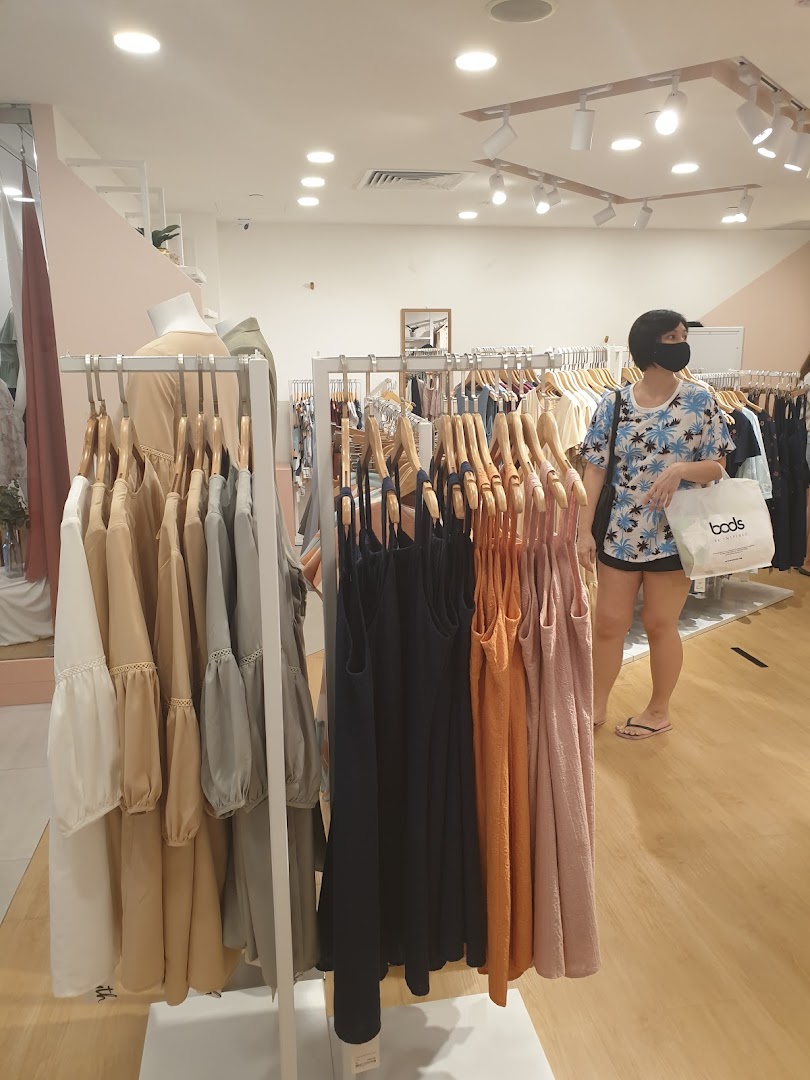 Interior of Fayth Plaza Singapura, featuring clothing racks with various apparel and a customer browsing.