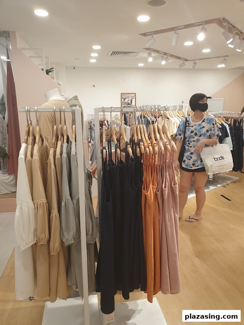 Interior of Fayth Plaza Singapura, featuring clothing racks with various apparel and a customer browsing.
