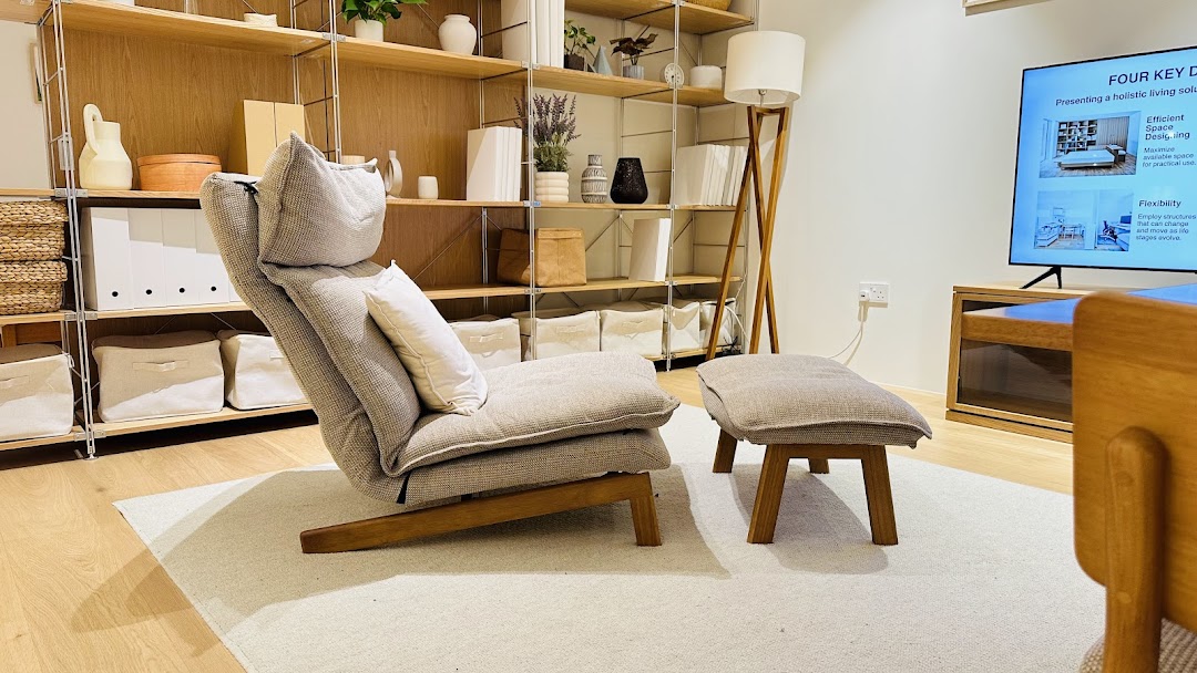 A cozy living room display featuring a comfortable chair, ottoman, and stylish shelving with home decor.