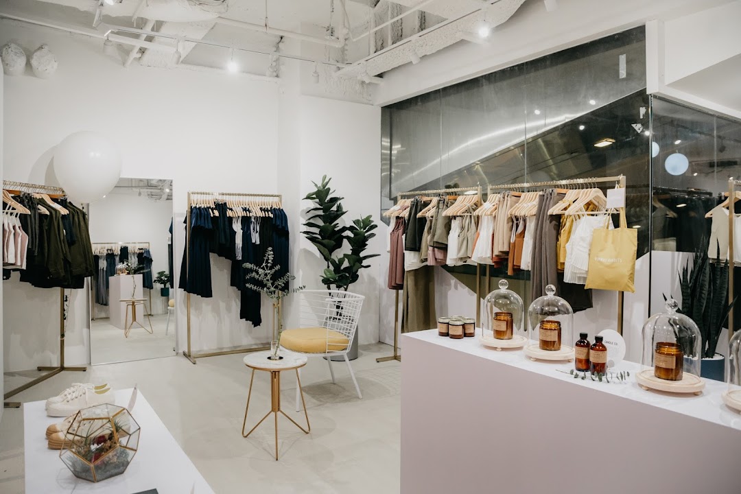 A bright, modern retail store interior featuring clothing racks, lifestyle products, and minimalist decor.