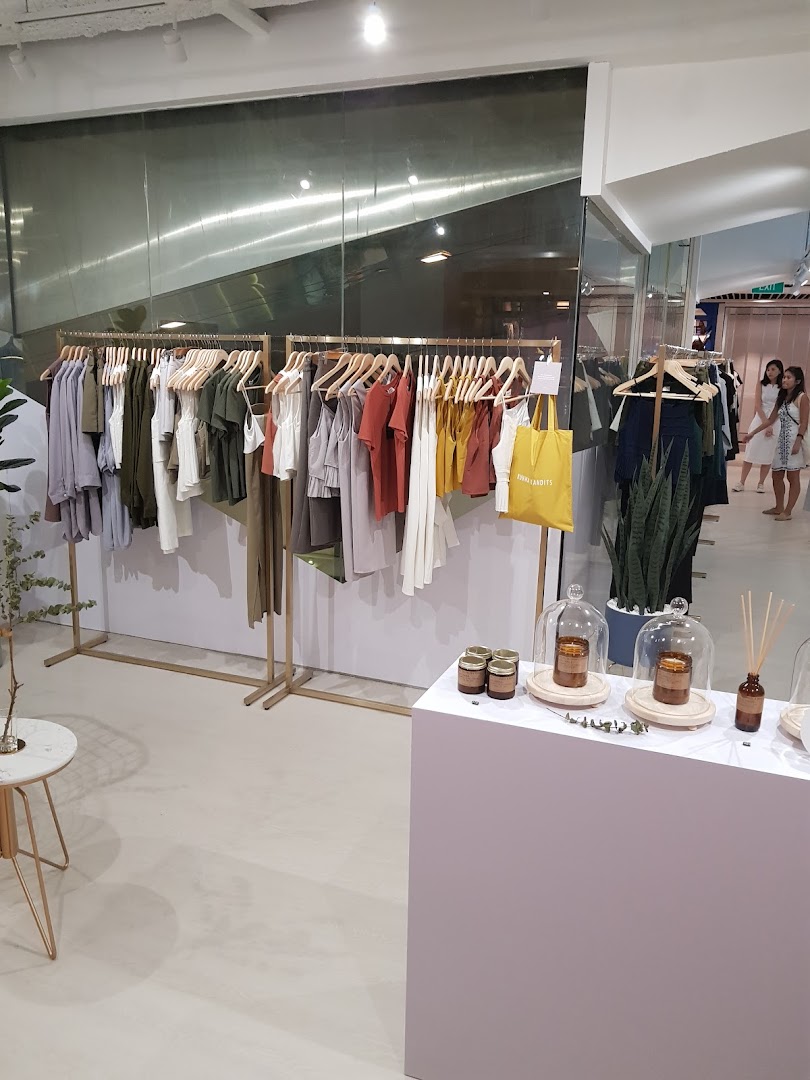 Interior view of a modern clothing boutique with racks of apparel and a display table.