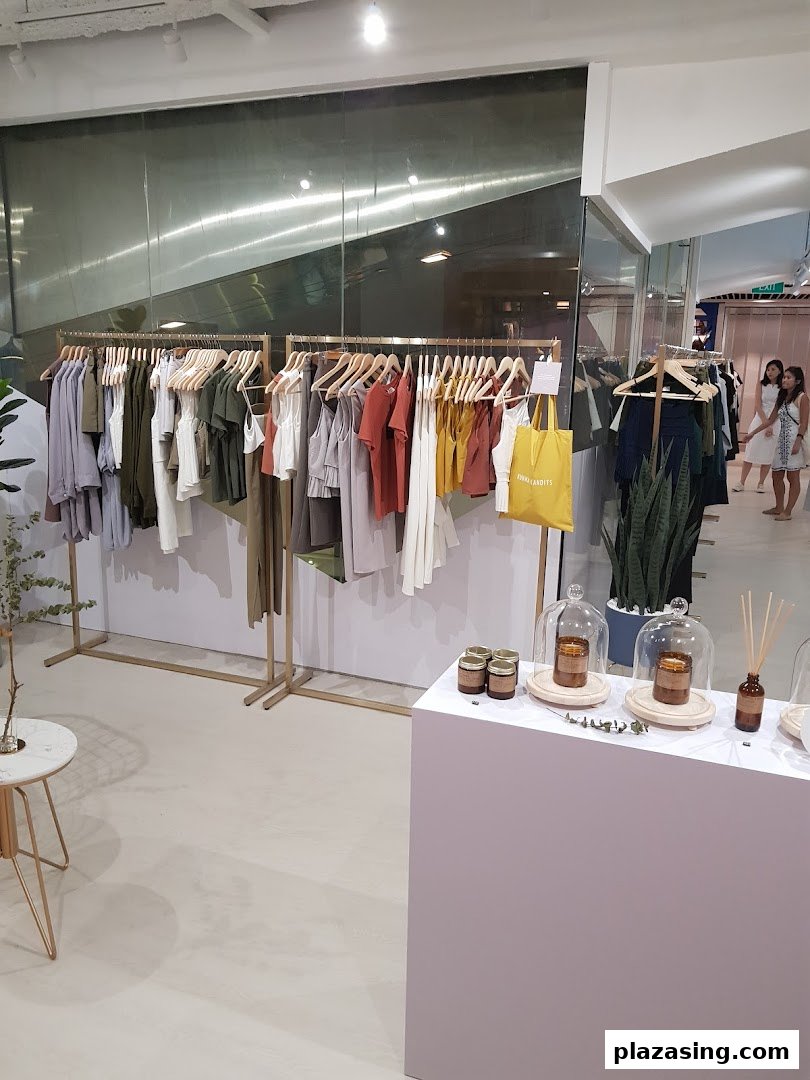 Interior view of a modern clothing boutique with racks of apparel and a display table.