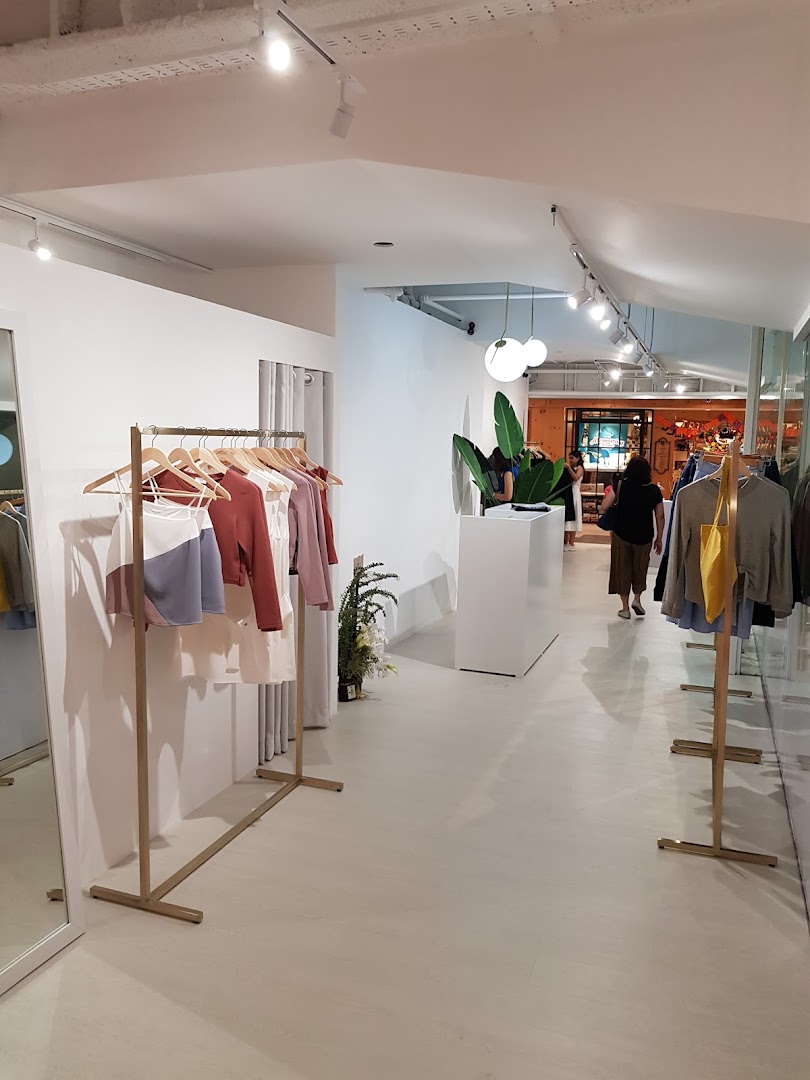 Interior view of a modern clothing boutique with apparel displayed on racks and a customer browsing.